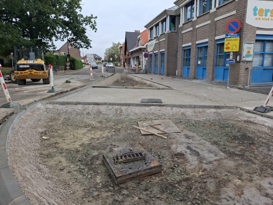 Wegwerkzaamheden met graafmachine en opengebroken straat bij een school. (vergroot foto)