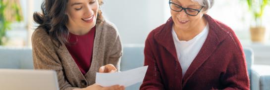 vrouw helpt een oudere vrouw met papierwerk